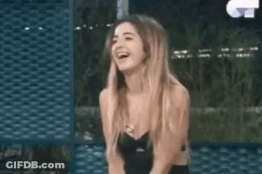 A Woman In A Black Dress Is Laughing While Sitting Down . GIF