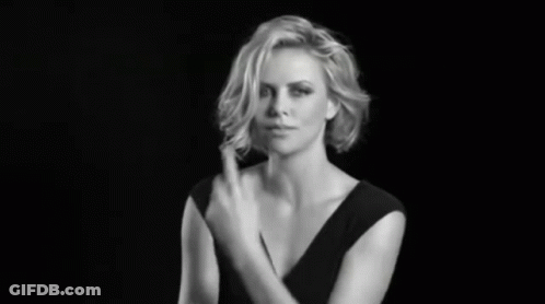 A Woman In A Black Dress Is Making A Gesture With Her Hand GIF
