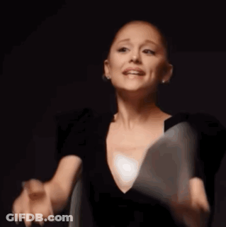 A Woman In A Black Dress Is Saying Gay While Holding A White Object In Her Hand GIF