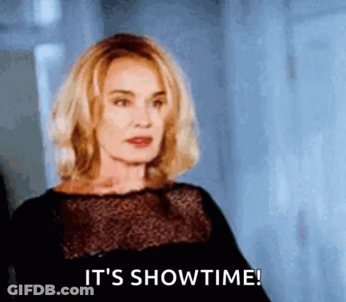 A Woman In A Black Dress Is Saying It 'S Showtime ! GIF
