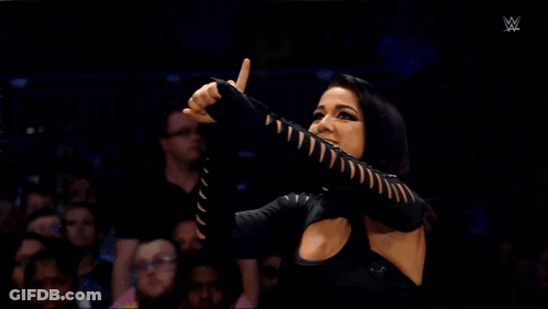A Woman In A Black Dress Is Screaming In Front Of A Crowd GIF