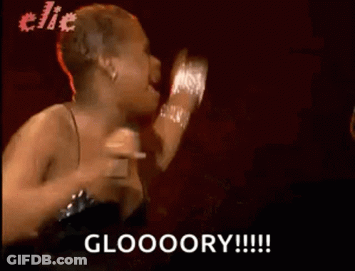A Woman In A Black Dress Is Singing Into A Microphone And Says Gloooory . GIF