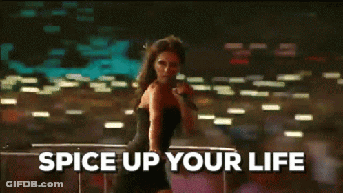 A Woman In A Black Dress Is Singing Into A Microphone With The Words Spice Up Your Life Above Her GIF