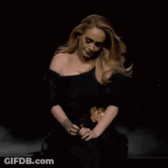 A Woman In A Black Dress Is Sitting Down GIF