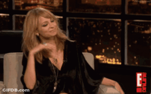 A Woman In A Black Dress Is Sitting In A Chair GIF