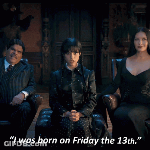 A Woman In A Black Dress Is Sitting In A Chair Next To A Man In A Suit And A Woman In A Dress GIF