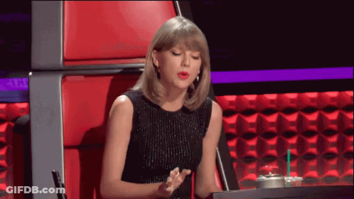 A Woman In A Black Dress Is Sitting In A Red Chair With A Cup Of Coffee GIF