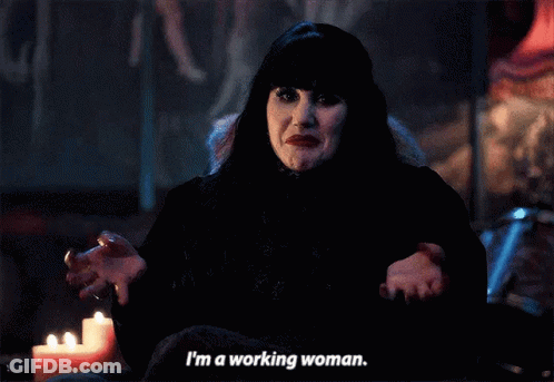 A Woman In A Black Dress Is Sitting In Front Of A Candle And Says I 'M A Working Woman . GIF