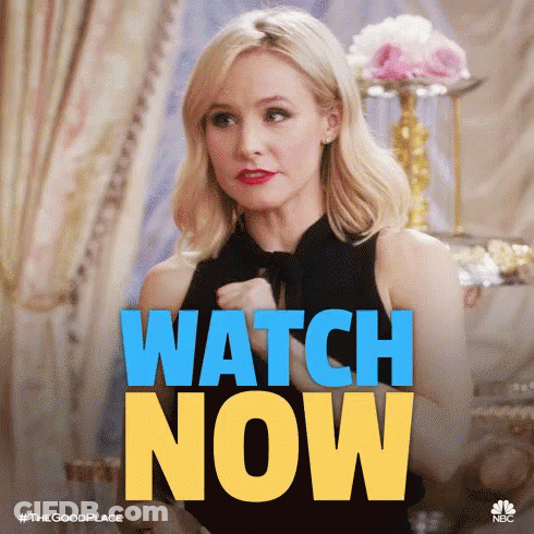 A Woman In A Black Dress Is Sitting In Front Of A Sign That Says Watch Now . GIF