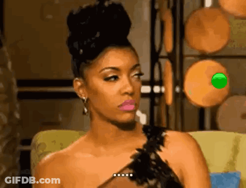 A Woman In A Black Dress Is Sitting On A Couch With A Green Object In Her Eye . GIF