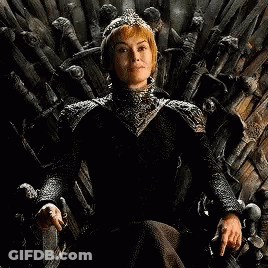 A Woman In A Black Dress Is Sitting On A Wooden Throne . GIF