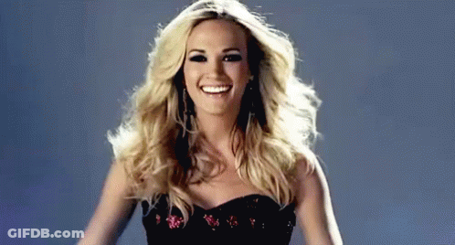 A Woman In A Black Dress Is Smiling And Dancing . GIF