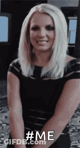 A Woman In A Black Dress Is Smiling And Holding Her Hands Together And Says `` # Me '' . GIF