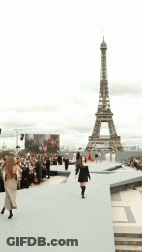 A Woman In A Black Dress Is Smiling And Walking . GIF