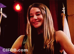 A Woman In A Black Dress Is Smiling In Front Of A Man In A Graduation Cap And Gown . GIF