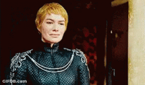 A Woman In A Black Dress Is Standing In Front Of A Door And Looking At The Camera . GIF