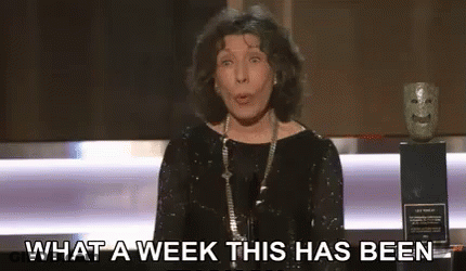 A Woman In A Black Dress Is Standing In Front Of A Microphone . GIF