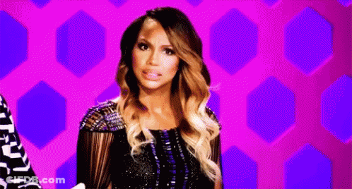A Woman In A Black Dress Is Standing In Front Of A Purple Background And Making A Funny Face . GIF