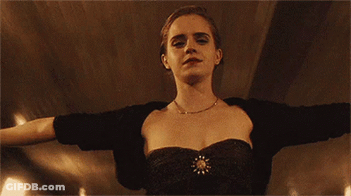 A Woman In A Black Dress Is Standing With Her Arms Outstretched And Looking At The Camera . GIF