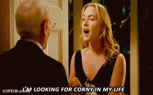A Woman In A Black Dress Says I 'M Looking For Corny In My Life To A Man In A Suit GIF