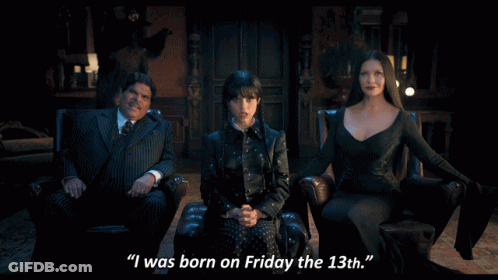 A Woman In A Black Dress Says " I Was Born On Friday The 13Th " Next To A Man In A Suit GIF