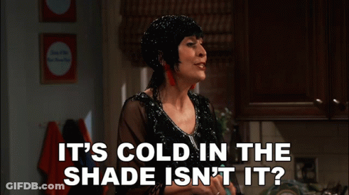 A Woman In A Black Dress Says " It 'S Cold In The Shade Isn 'T It " GIF