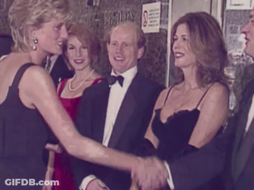 A Woman In A Black Dress Shakes Hands With A Man In A Tuxedo GIF