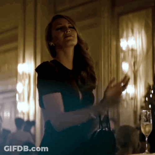 A Woman In A Black Dress Stands In A Dark Room GIF