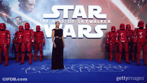 A Woman In A Black Dress Stands In Front Of A Star Wars Poster GIF