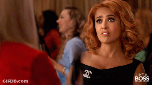 A Woman In A Black Dress With A Chanel Brooch GIF