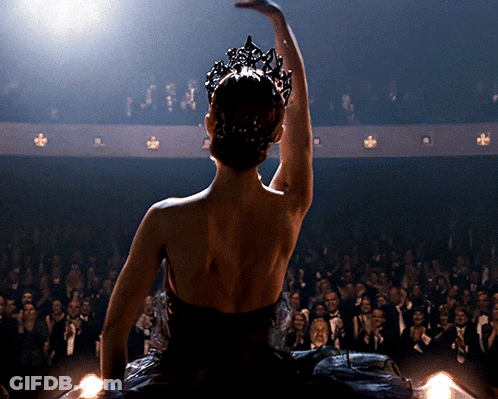 A Woman In A Black Dress With A Crown On Her Head Is Dancing In Front Of A Crowd GIF