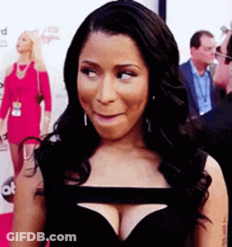 A Woman In A Black Dress With A Plunging Neckline Is Making A Funny Face . GIF