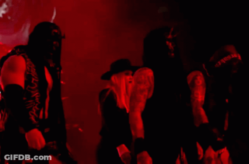 A Woman In A Black Hat Is Standing Next To A Man In A Black Shirt That Says ' Slayer ' GIF