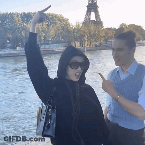 A Woman In A Black Hoodie Is Pointing At Something In The Distance GIF