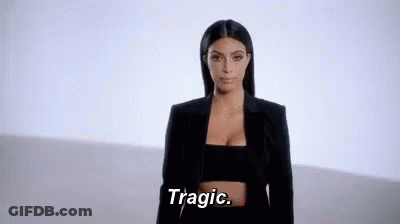 A Woman In A Black Jacket And Crop Top Is Standing In Front Of A White Wall And Saying Tragic . GIF