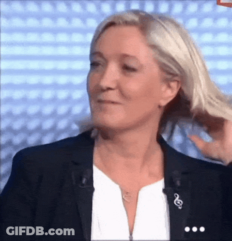 A Woman In A Black Jacket And White Shirt Is Holding Her Hair GIF