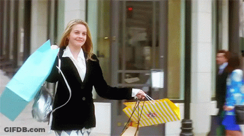 A Woman In A Black Jacket Is Carrying Shopping Bags In Front Of A Building GIF