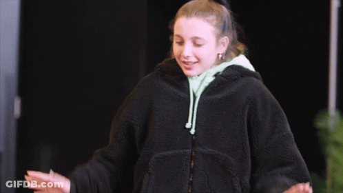 A Woman In A Black Jacket Is Giving A Thumbs Up Sign GIF