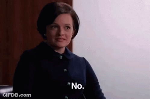 A Woman In A Black Jacket Is Sitting In A Chair And Saying No . GIF