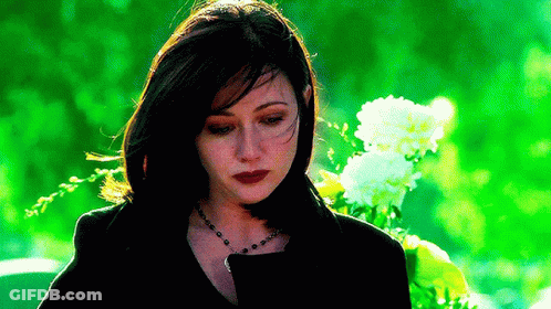 A Woman In A Black Jacket Is Standing In Front Of A Bouquet Of Flowers . GIF
