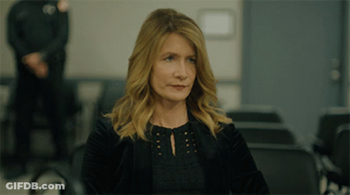 A Woman In A Black Jacket Sits In A Waiting Room GIF