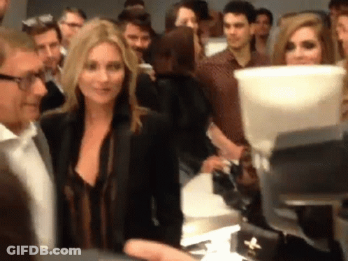 A Woman In A Black Jacket Stands In A Crowd GIF