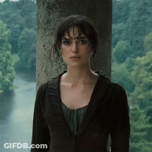 A Woman In A Black Jacket Stands In Front Of A Body Of Water GIF