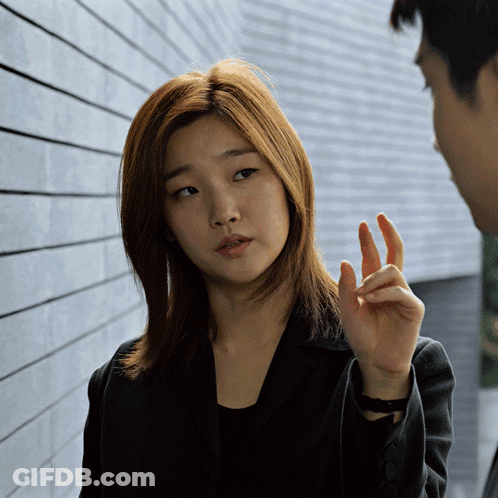A Woman In A Black Jacket Talks To A Man In A Suit GIF