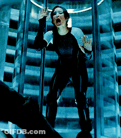 A Woman In A Black Jumpsuit Is Screaming In A Glass Elevator GIF