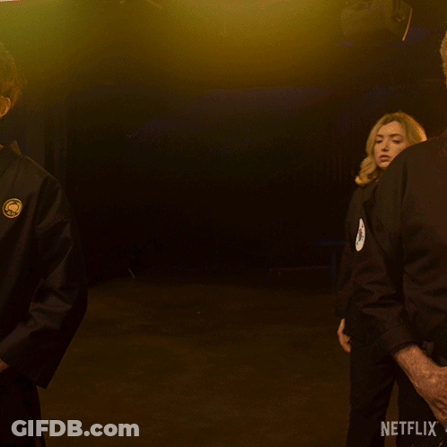 A Woman In A Black Karate Uniform Is Standing In Front Of A Netflix Sign GIF