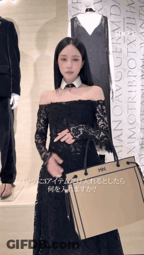 A Woman In A Black Lace Dress Is Holding A Bag That Says Mn On It GIF