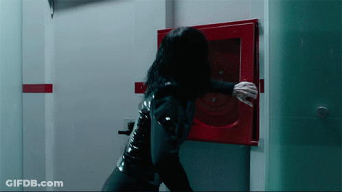 A Woman In A Black Latex Suit Is Reaching For A Red Fire Hydrant GIF