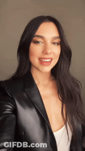 A Woman In A Black Leather Jacket Is Smiling GIF