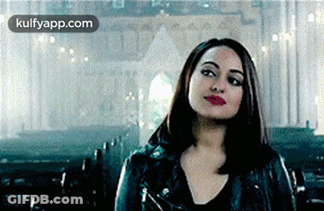 A Woman In A Black Leather Jacket Is Standing In A Church . GIF